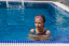 A child showing signs of summer stress and anxiety in the pool, illustrating how school breaks and changes in routine can affect kids’ emotional well-being.
